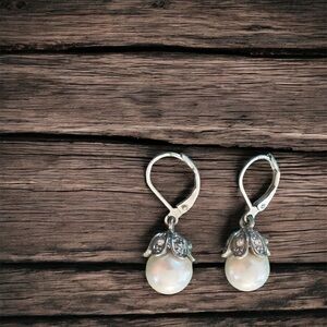Silver dangle pearl drop earrings with silver detailing at the top.